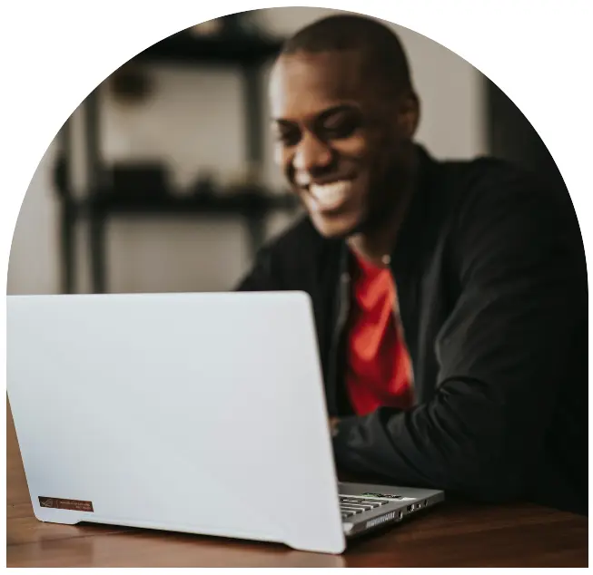 Man smiling while typing on laptop during online consultation